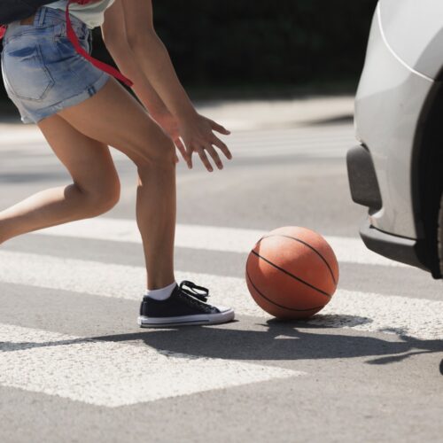 A young woman crossing the street to get her basketball