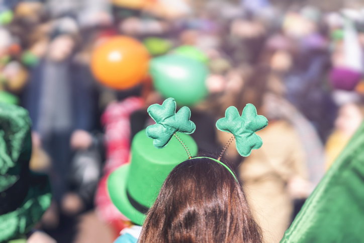 Clover head decoration on head of girl close-up. Saint Patricks day, parade in the city, selective focus, copy space