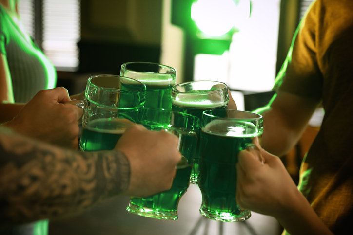 Group of friends toasting with green beer in pub, closeup. St. Patrick's Day celebration